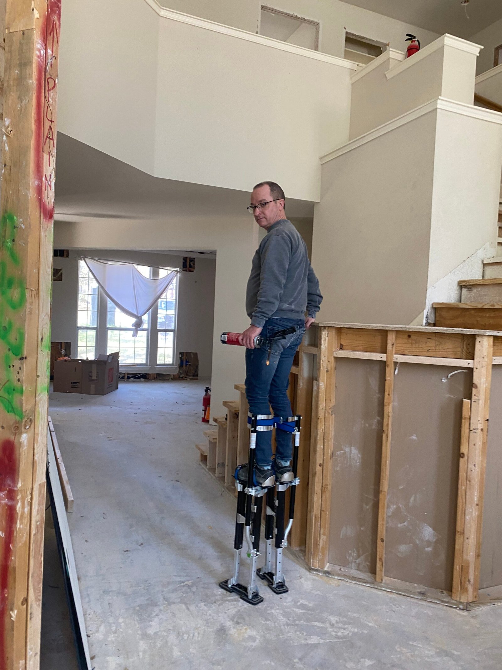 Smith walks through a house mid construction using scaffolding stilts.