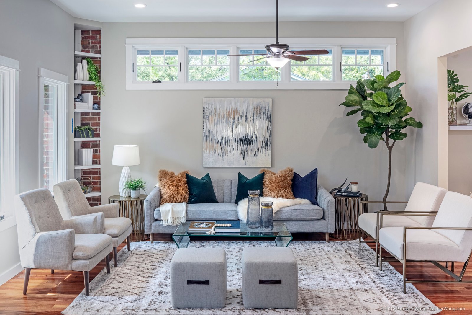 Living room with gray sofa, patterned rug, plants, and gallery wall art beneath tall windows (angle 3)