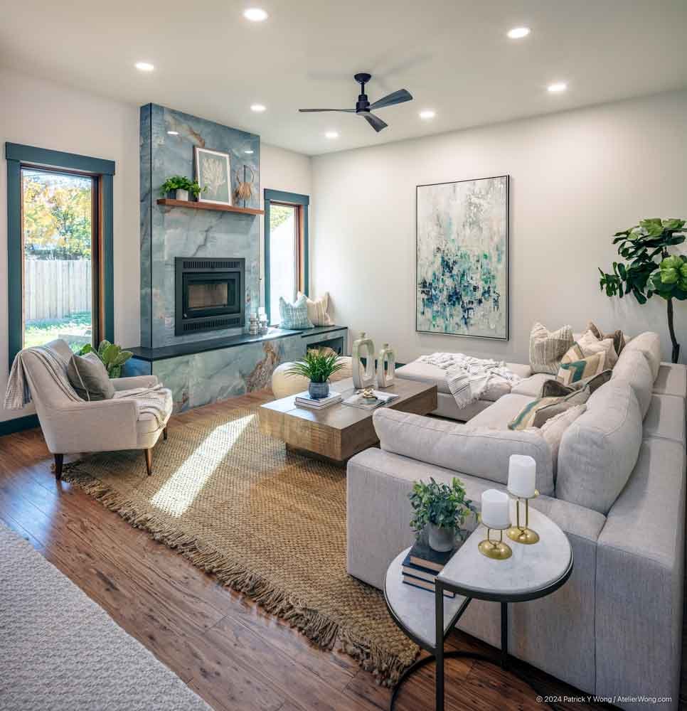 Living room with sectional sofa, fireplace, gallery art, and a kitchen visible in the background