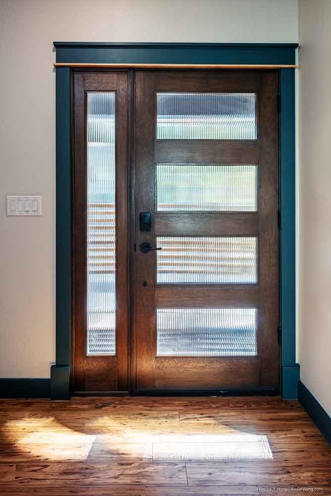 Close-up of a wood-paneled front door with frosted glass panels and black hardware