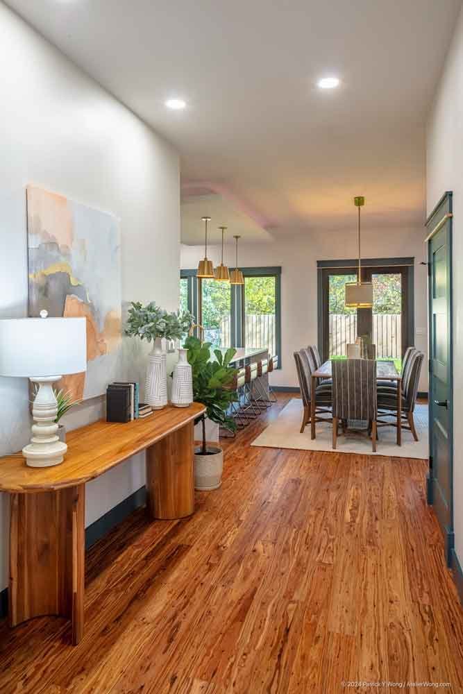 Entryway hall with console table, lamp, artwork, and a dining area visible beyond
