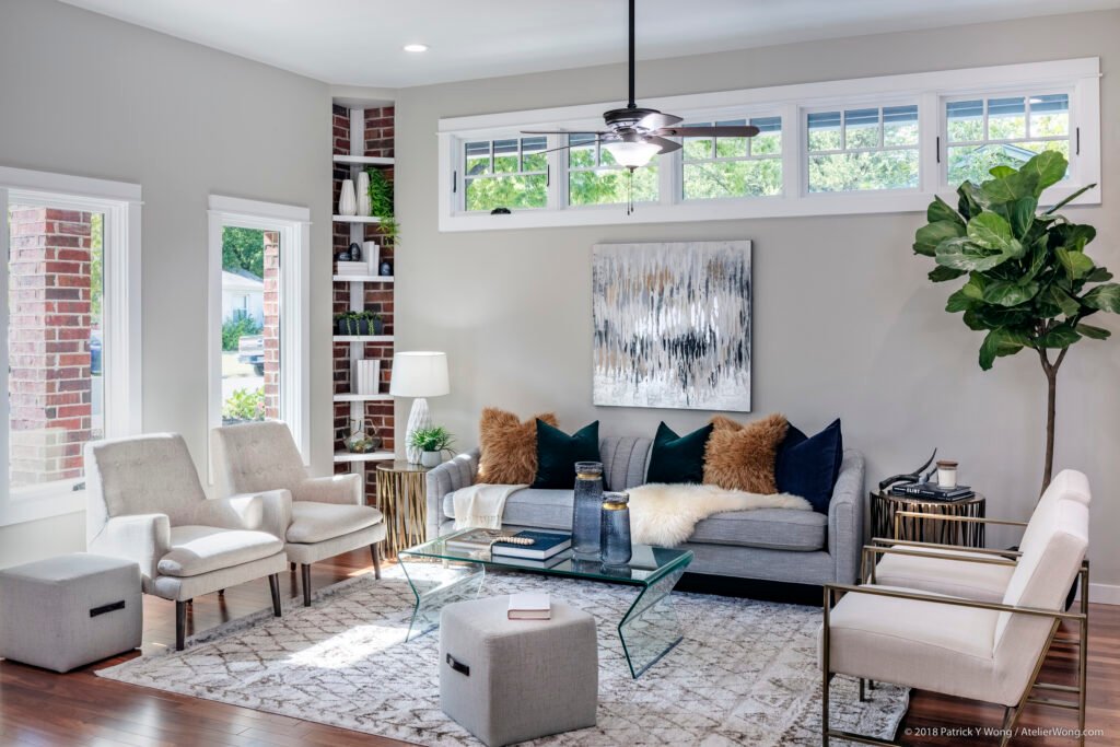 Living room with gray sectional sofa, glass coffee table, patterned rug, and gallery wall art