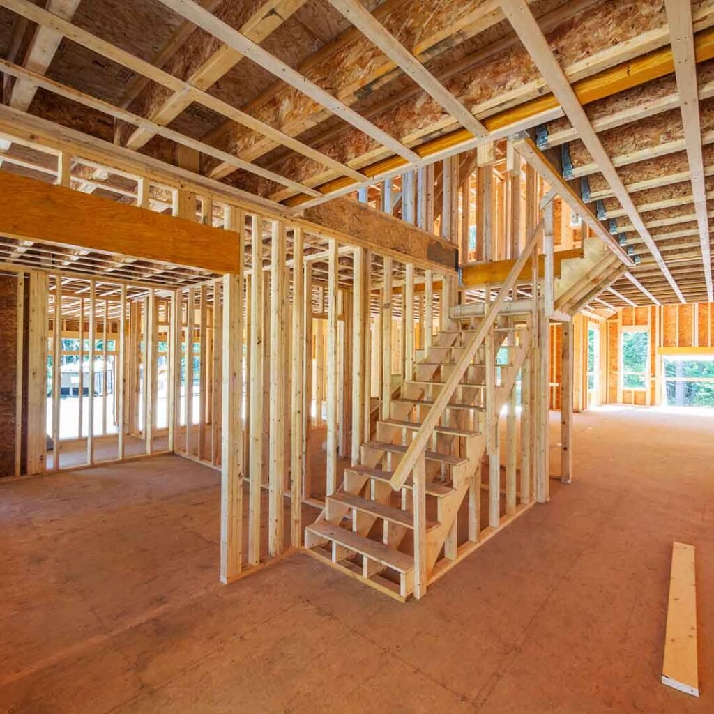 Wood-framed staircase and open second-story framing inside a house under construction.
